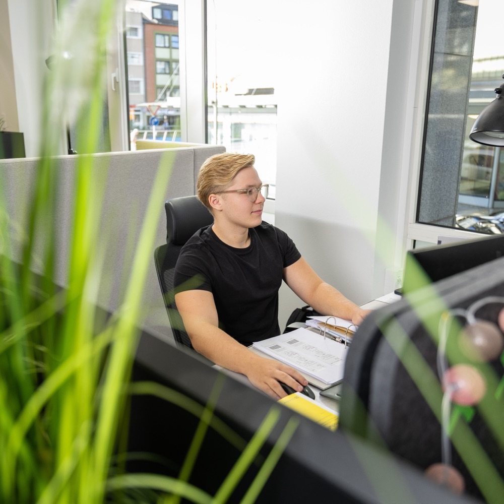 Mitarbeiter von H+ arbeitet konzentriert am Schreibtisch im Büro